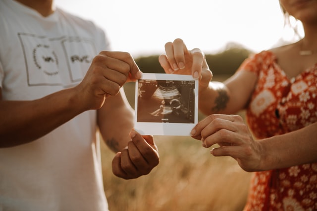 couple holding ultrasound image of their baby